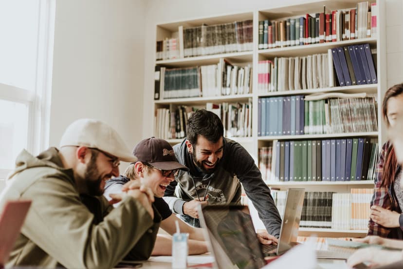 Um grupo de pessoas se diverte enquanto olha para a tela do computador. Estudar línguas pode ser uma atividade altamente social e divertida.